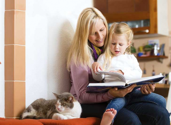 Image: Mum reading a book to child in at home