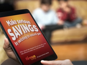 Image: person holding an ipad with the screen showing serious savings with firmus energy