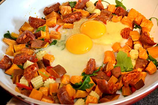 Image: firmus fuel two eggs added to a pan with chorizo